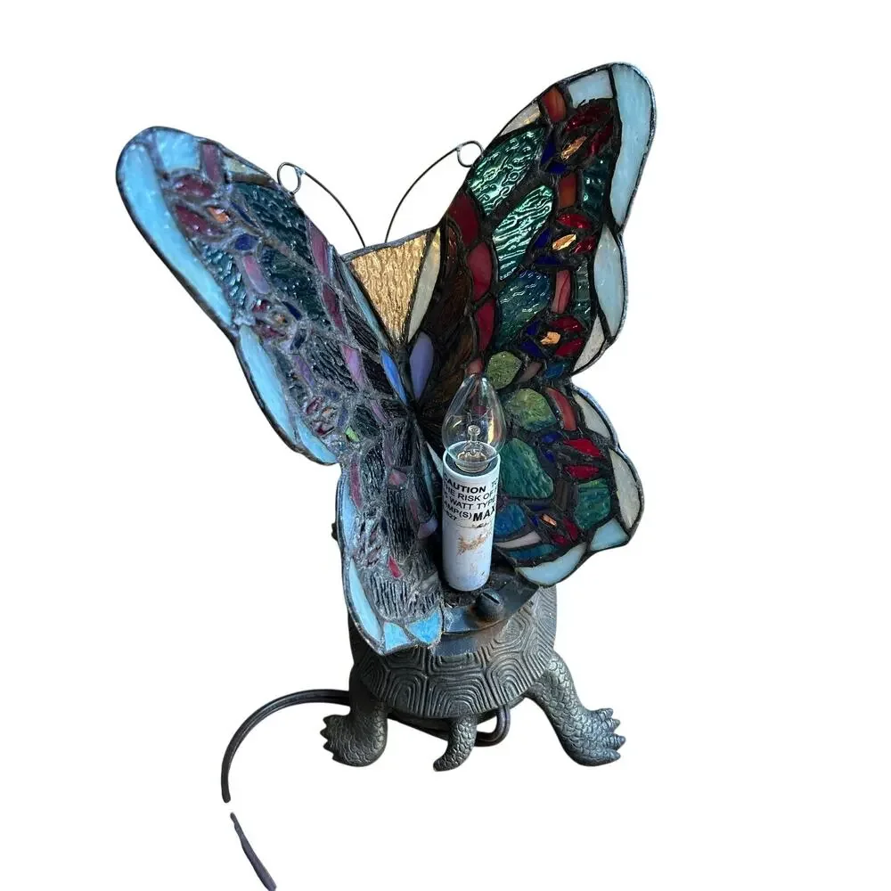 Vintage Tiffany style stained glass butterfly lamp resting on a brass turtle